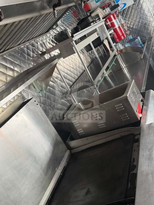 Interior view of a fully equipped 1999 Chevrolet P30 food truck kitchen with stainless steel appliances and storage.