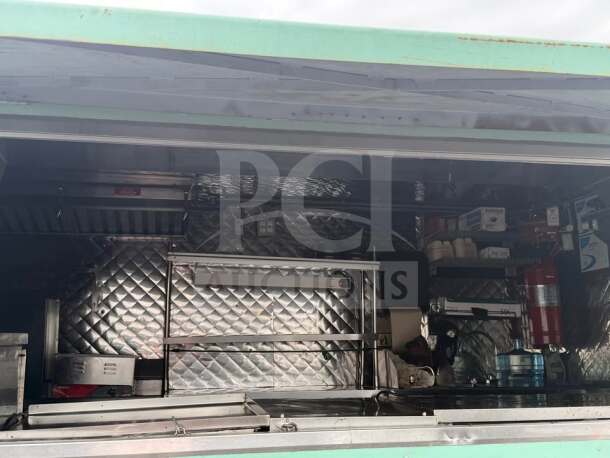 Interior of a 24' Chevrolet P30 food truck with a fully equipped commercial kitchen, stainless steel surfaces, and storage racks.