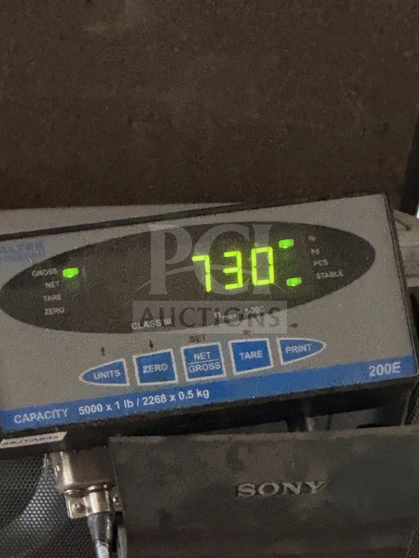 Digital scale display showing weight of 730 pounds, indicating the pallet of stainless steel scrap metal for auction.