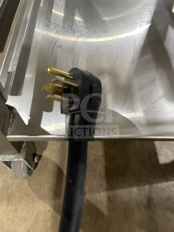 Close-up of Alto Shaam commercial electric oven's 208-240V power plug on stainless steel surface with casters.