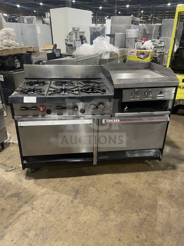 Garland stainless steel 6-burner gas range with raised griddle, double oven, broiler, cheese melter, and overhead salamander.