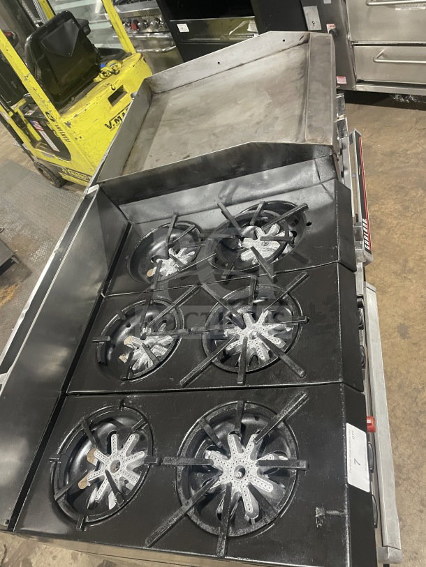Garland stainless steel 6-burner range with raised flat griddle, double oven, broiler, cheese melter, backsplash, and shelf.