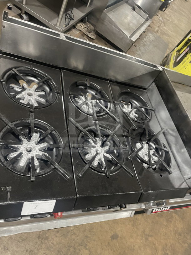 Garland stainless steel 6-burner gas range with griddle, double ovens, and broiler. Features backsplash and overhead shelf.