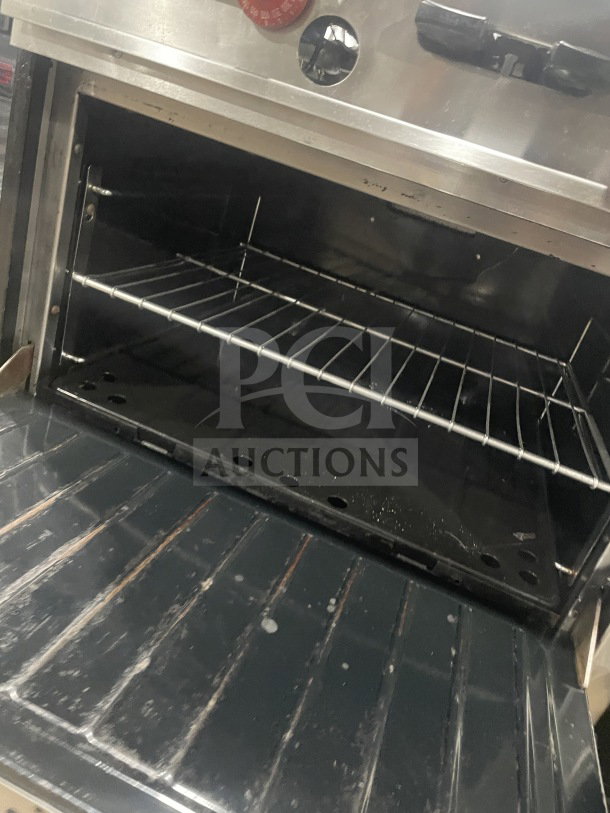Garland stainless steel double oven with wired rack. Includes broiler, cheese melter, and overhead salamander shelf.