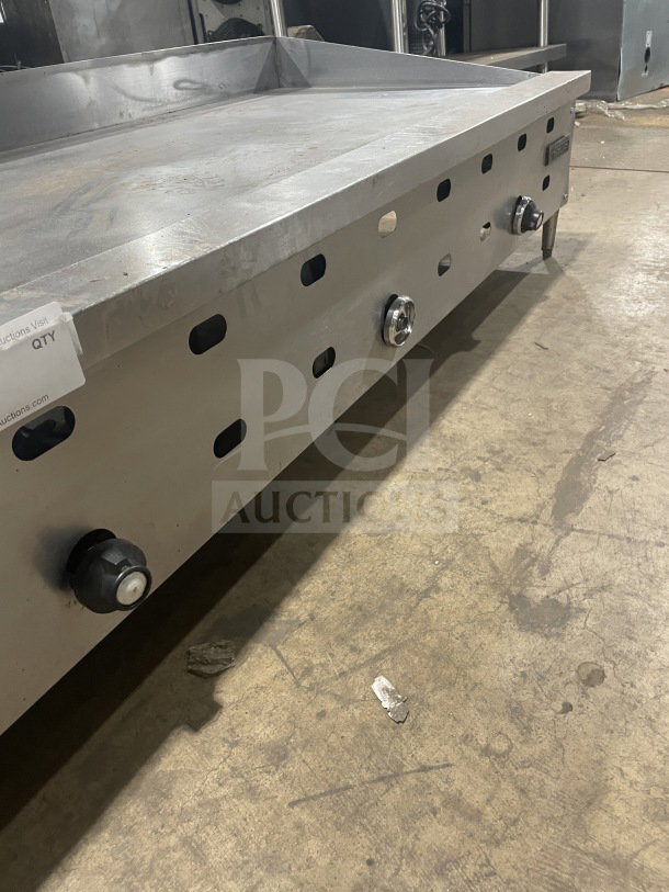 Garland commercial stainless steel countertop gas griddle on legs. Features control knobs, slight surface wear, and durable design.
