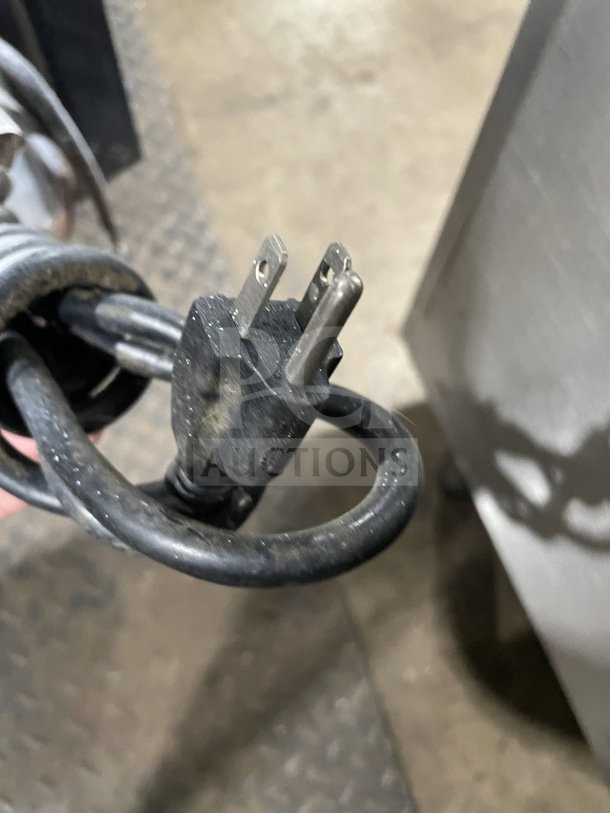 Close-up of a black electrical plug with two prongs, part of a Tor-Rey commercial deli merchandiser, Model TEC13OL UL, 120V.