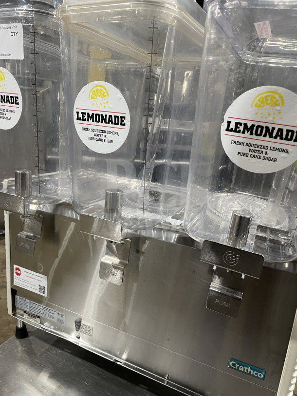 Crathco D354 beverage machine with 3 hoppers, stainless steel base, 115V, on legs; clear hoppers labeled "Lemonade."