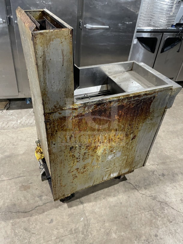 Commercial stainless steel gas-powered deep fryer with backsplash, on casters. Visible rust and wear on exterior surfaces.