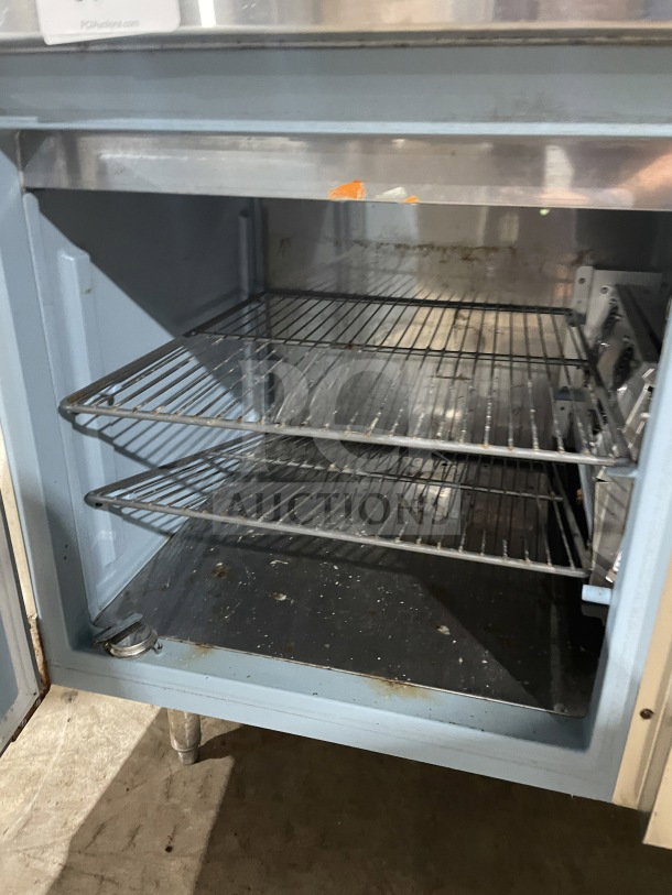Delfield stainless steel pizza prep table with refrigerated enclosed storage, double overhead shelf, chrome rack, 115V, on legs.