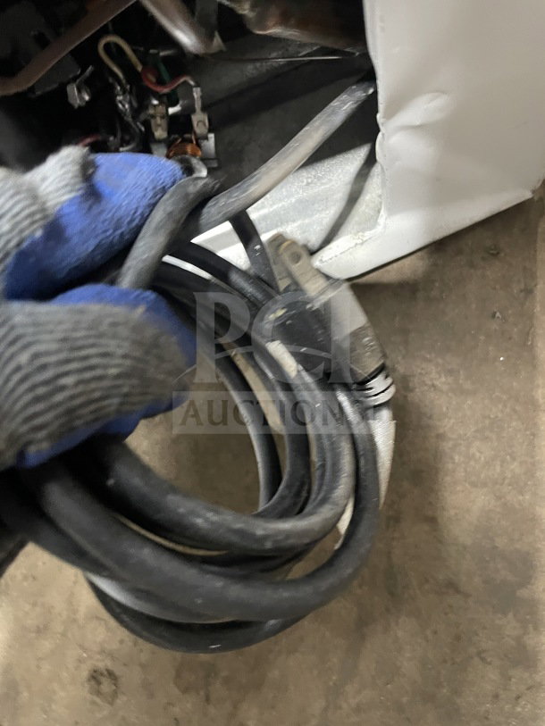 Coiled black power cable attached to the commercial white curved glass 46" ice cream dipping cabinet.