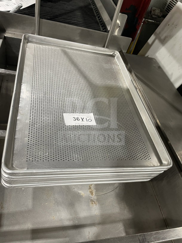 Commercial stainless steel perforated full-size sheet pan in good condition, stack of ten, label reads "36 X 10".