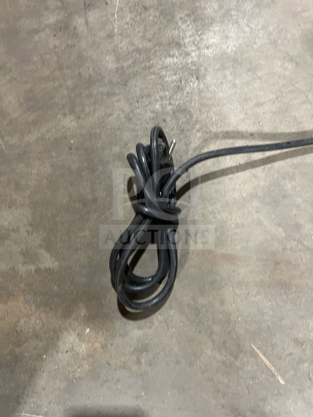 Coiled black power cord on a concrete floor, possibly for RCA RFR320-B-RED-COM refrigerator and freezer.