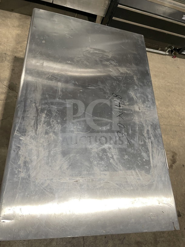 L&J Commercial stainless steel worktop table with undershelf. Visible surface scratches, markings indicating size 30x48. Features adjustable legs.
