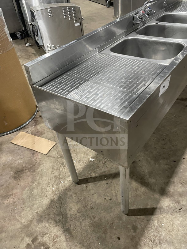 Krowne stainless steel 3-compartment underbar sink with side drainboards and backsplash on legs, in good condition.