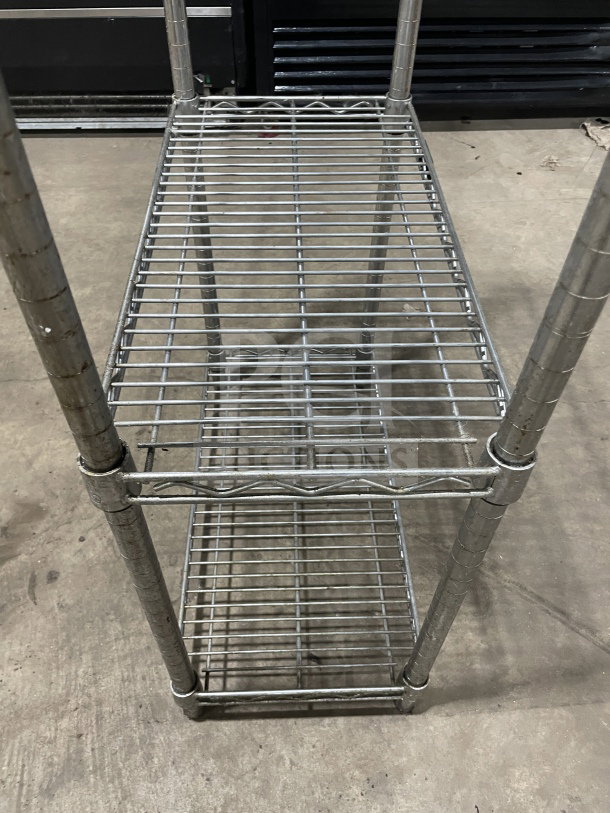 Uline Commercial 4-Tier Chrome Wire Shelving Unit, sturdy metal construction, light wear, ideal for industrial storage.
