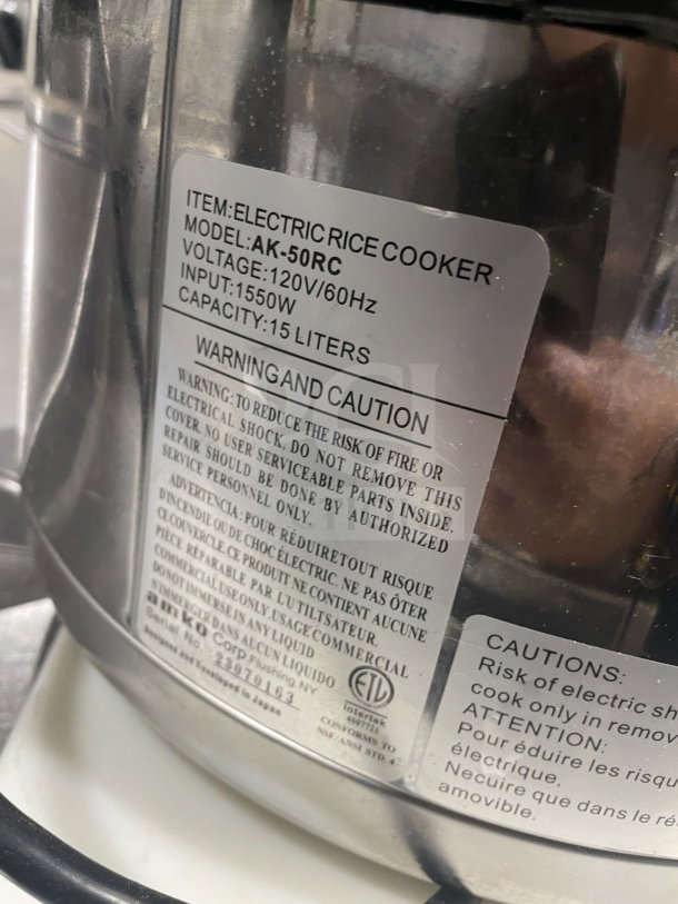 Amko AK-50RC stainless steel electric rice cooker, 120V, 1550W, 15L capacity, with caution labels and serial number 23079163.