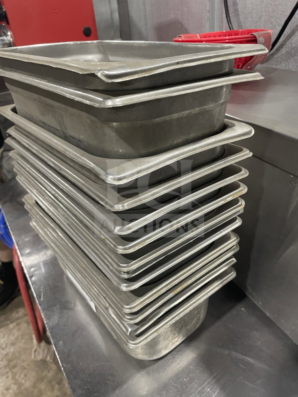 Stack of commercial stainless steel food storage trays, suitable for sauces or salads, shown in used condition.