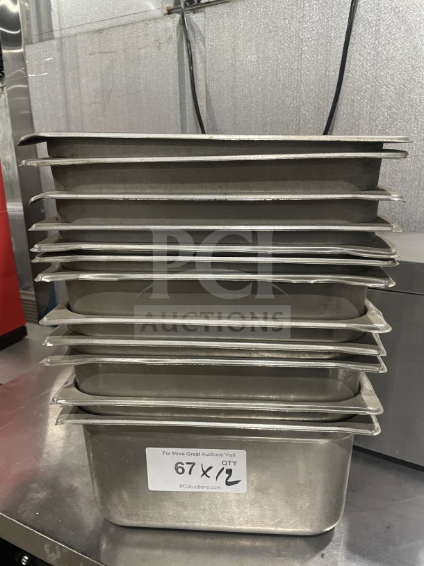 Commercial stainless steel food storage containers in a stack, labeled "67 x 12," indicating 12 items per bid.