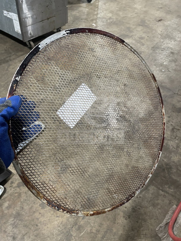 Commercial stainless steel pizza holder, heavy duty, with mesh design and visible wear, ideal for restaurant use.