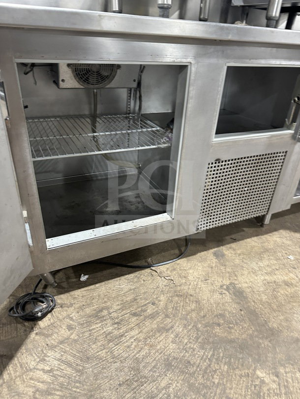 Delfield stainless steel undercounter refrigerator chef base with integrated open storage shelves, chrome plated wire rack.