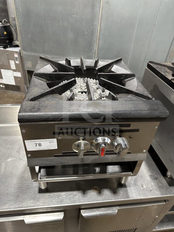 Commercial stainless steel gas stock pot range with triple knob configuration, sturdy cast iron grate, lightly used condition.