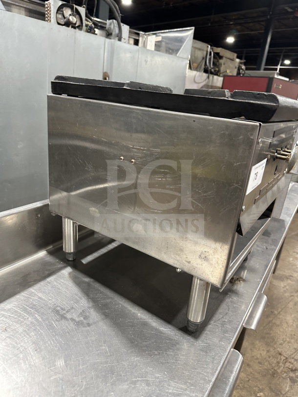 Commercial stainless steel gas stock pot range with triple knob configuration, sturdy legs, and well-maintained condition.
