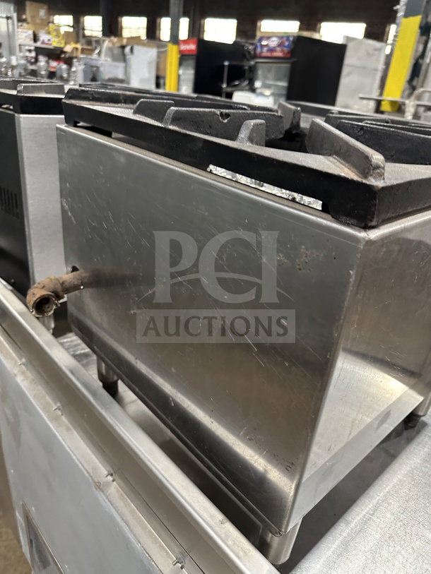 Commercial stainless steel gas stock pot range with triple knob configuration, used condition, visible wear.