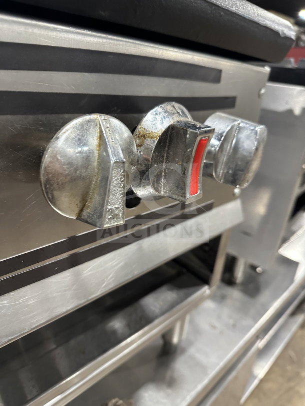 Commercial stainless steel gas stock pot range with triple knob configuration. Shiny finish, visible wear, ideal for high-capacity cooking.