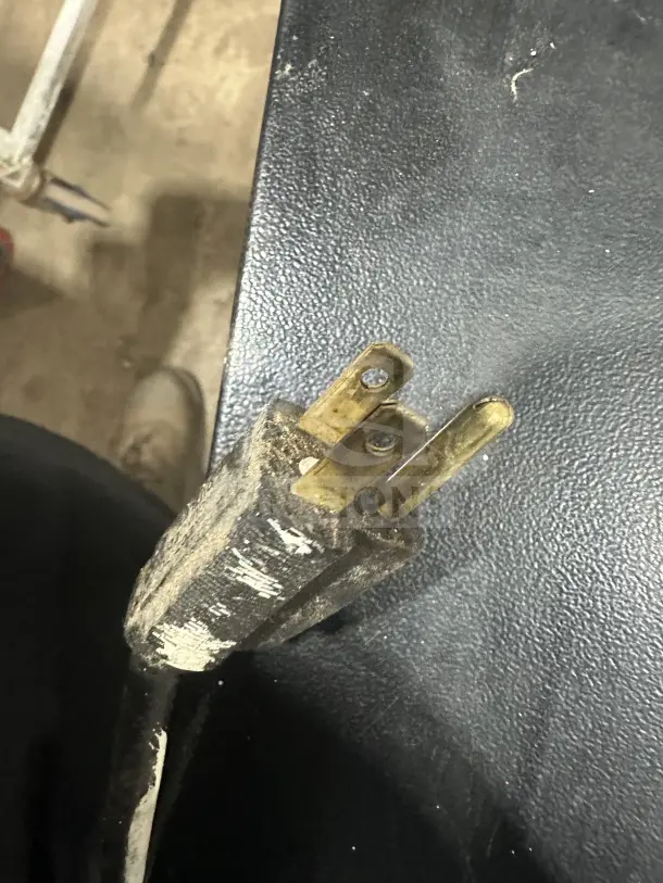 The image shows a worn, three-prong power plug, possibly for the Commercial 4-Tier Electric Pizza Merchandiser.