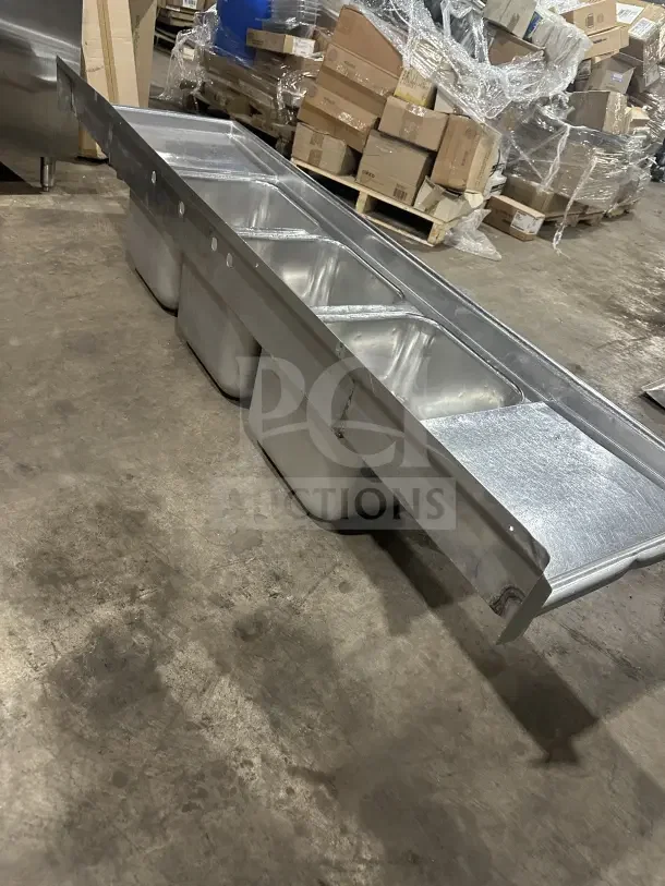 Commercial stainless steel 3-compartment sink with two side drainboards and sturdy legs. Ideal for kitchens, durable condition.