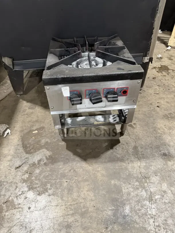 Commercial stainless steel gas-powered single burner stock pot range with control knobs, on legs, in used condition.