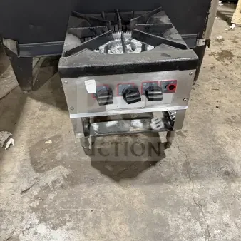 Commercial stainless steel gas-powered single burner stock pot range with control knobs, on legs, in used condition.