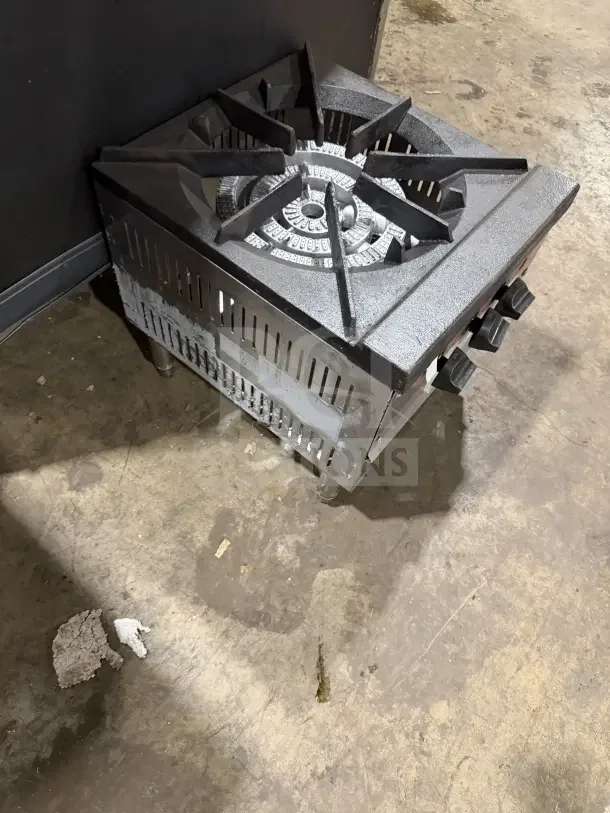Commercial stainless steel gas-powered countertop single burner stock pot range with sturdy legs, visible wear, heavy-duty design.