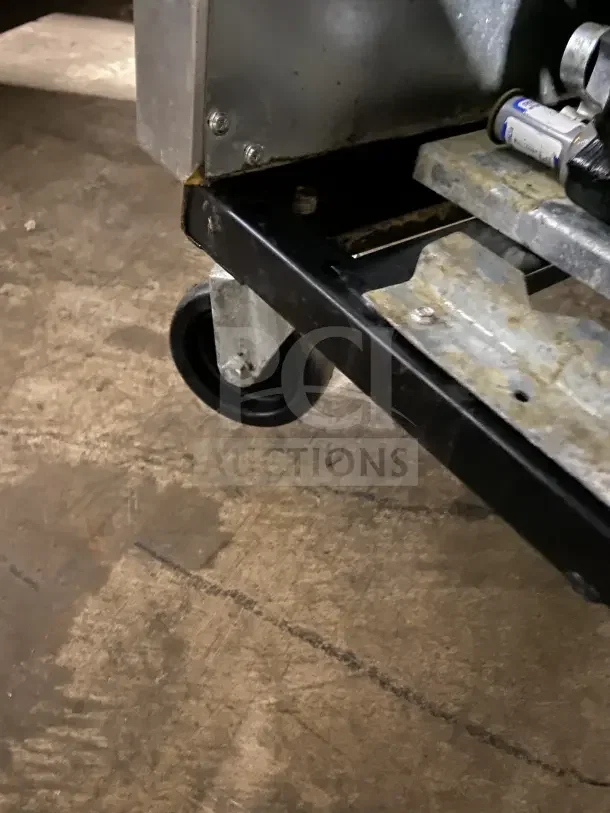 Close-up view of caster and bottom corner of True T35F commercial stainless steel refrigerator, showing some wear.
