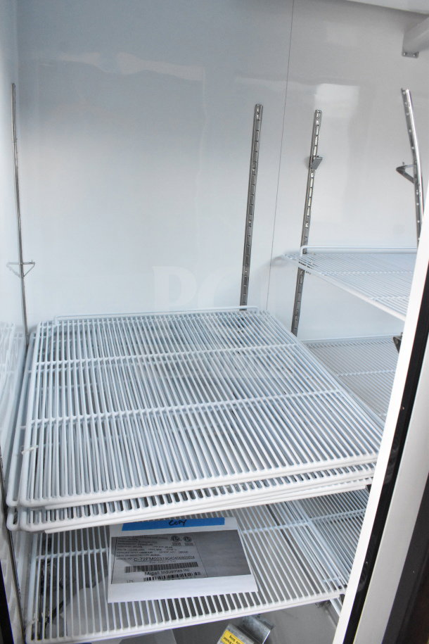 Brand new Migali C-72FM commercial 3-door reach-in freezer, interior view with shelving, serial C-72FM00319040400920014.