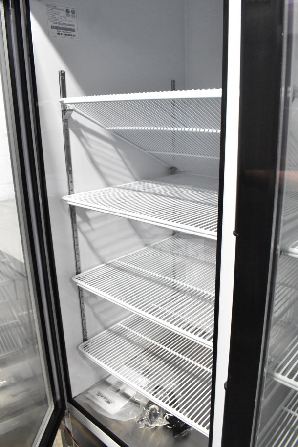 Alt text: "Brand new Migali C-72FM 3-door commercial freezer merchandiser, 2019 model, 115/208-230 volts, featuring multiple wire shelves."