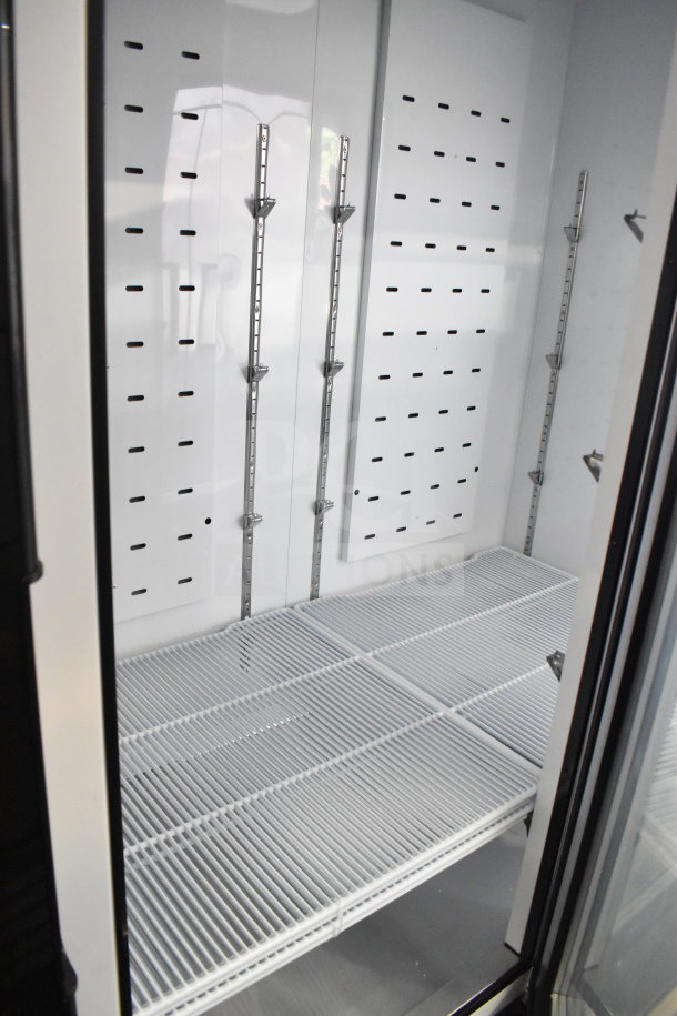 Brand new Migali C-72FM-HC 3-door reach-in freezer interior, wire racks inside, in excellent condition, on casters.