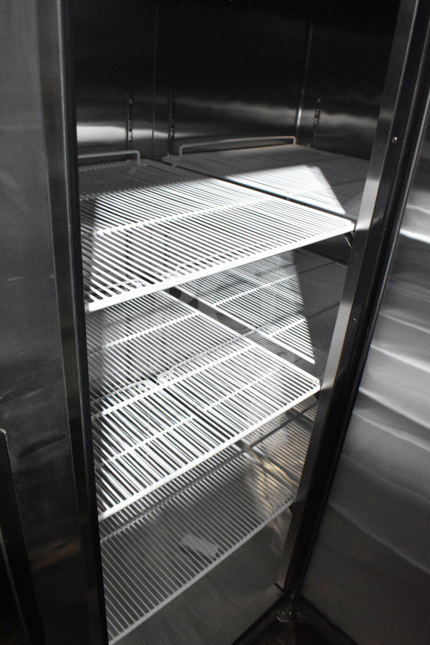 Brand new Migali C-3R 3-door commercial freezer interior with adjustable wire shelves, on commercial casters.