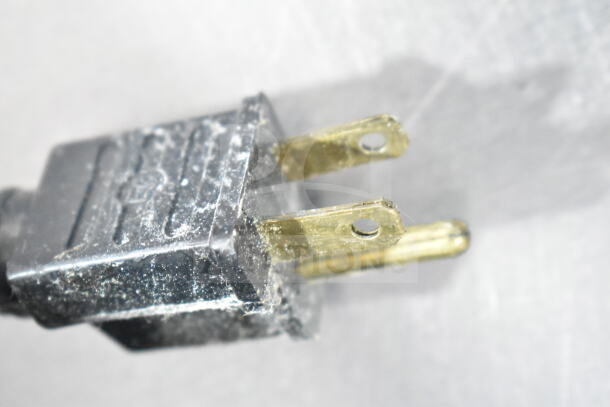 Close-up of a worn electrical plug with two metal prongs showing signs of wear and dirt.