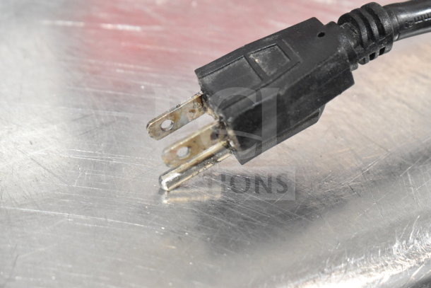 Close-up of a power plug for Avantco 184T140 toaster oven, showing prongs in used condition on a metallic surface.