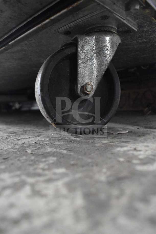 Close-up of a caster wheel on a True TUC-72 commercial undercounter cooler. Appears in used condition.