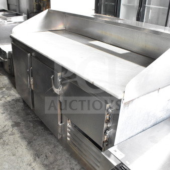 Commercial 3-door cooler with stone countertop and casters. Stainless steel finish. Good condition for restaurant use.