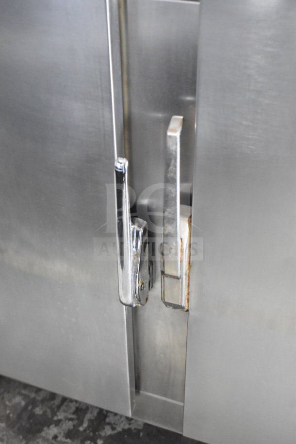 Commercial 3-door cooler with stone countertop and shiny metal handles, on commercial casters. Appears in good condition.