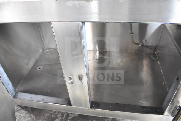 Commercial 3-door cooler with stone countertop on casters, stainless steel interior, visible piping, good used condition.