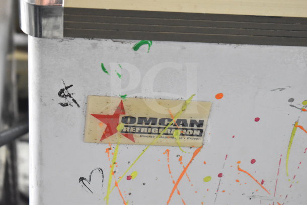 Omcan XS-200 Chest Freezer Merchandiser with visible wear, colorful paint splatters, Omcan logo tag, 110 Volts, 1 Phase.