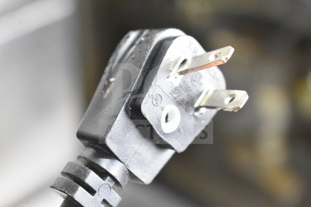 Close-up of a power plug for the Omcan XS-200 Chest Freezer Merchandiser, 110 V, 1 Phase, showing prongs and safety markings.