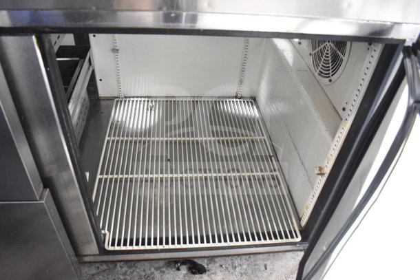 True TPP-67D-2 commercial pizza prep table interior, showing wire shelving and cooling fan. 115V, 1 Phase.