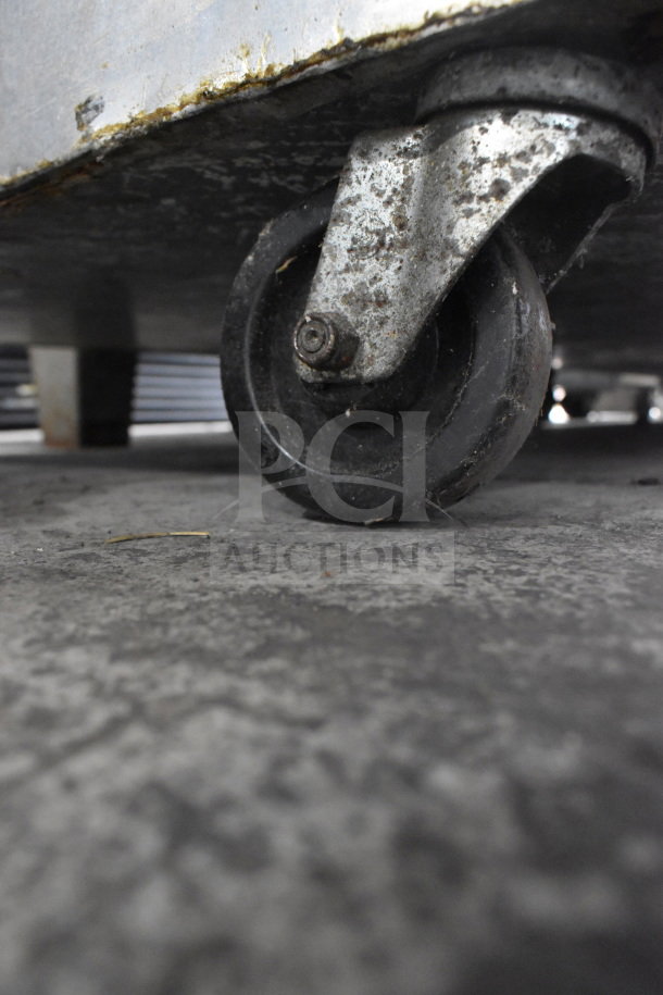 Commercial caster on Continental 2RE Reach In Cooler, highlighting wheel and metal housing, shows signs of wear and use.
