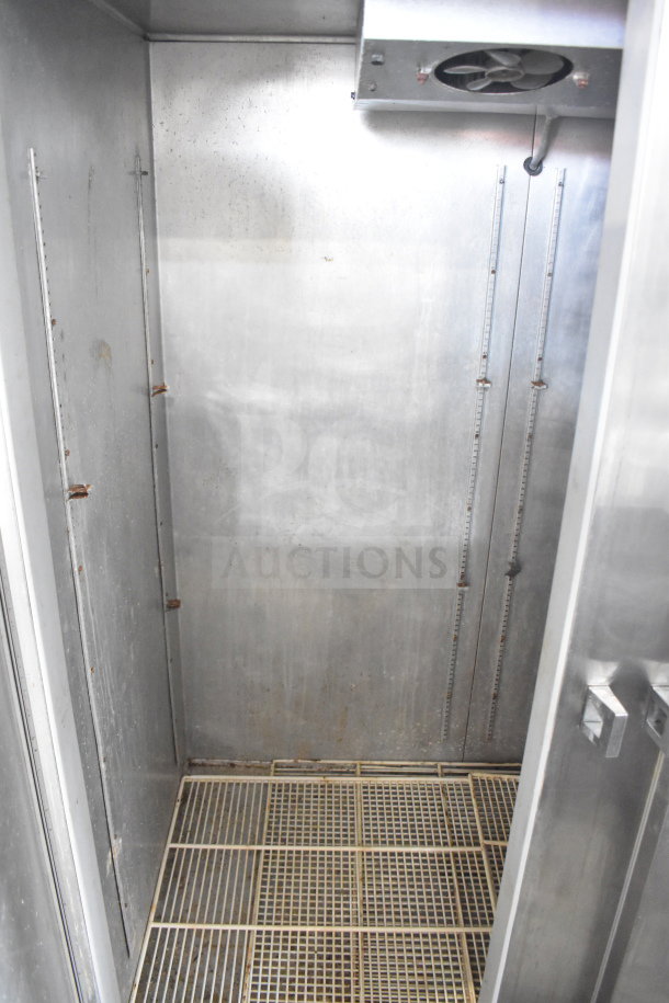 Continental 2RE commercial reach-in cooler interior, showing stainless steel walls and shelving tracks. Condition shows wear.