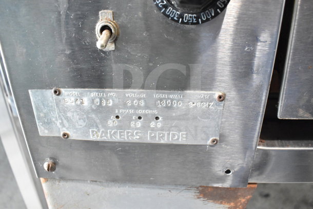 Bakers Pride E541 commercial pizza oven with two decks, metal legs. 208 volts, 3 phase. Visible label with specs and model details.